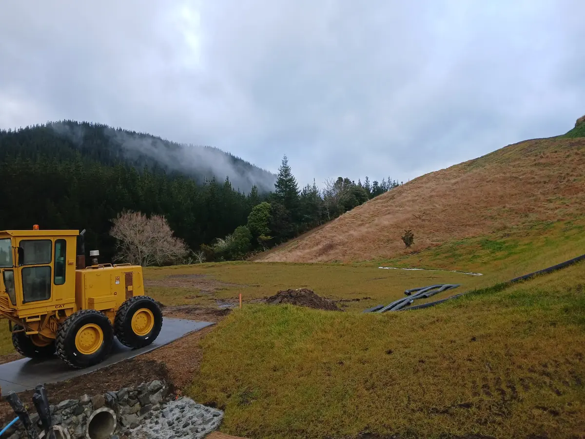 A grader parked on a newly formed lot platform overlooking misty forested hills
